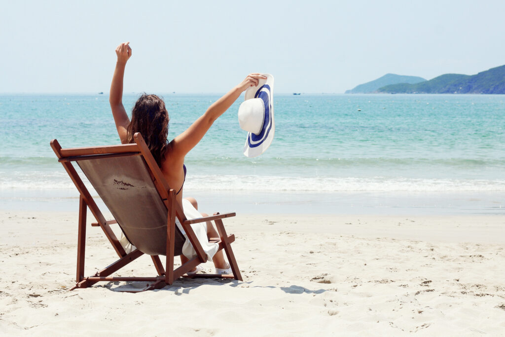 young,brunette,woman,sitting,on,the,beach,,looking,at,the